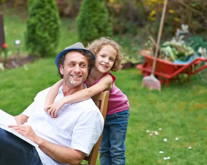 Smiling daughter hugs happy father in garden in summer