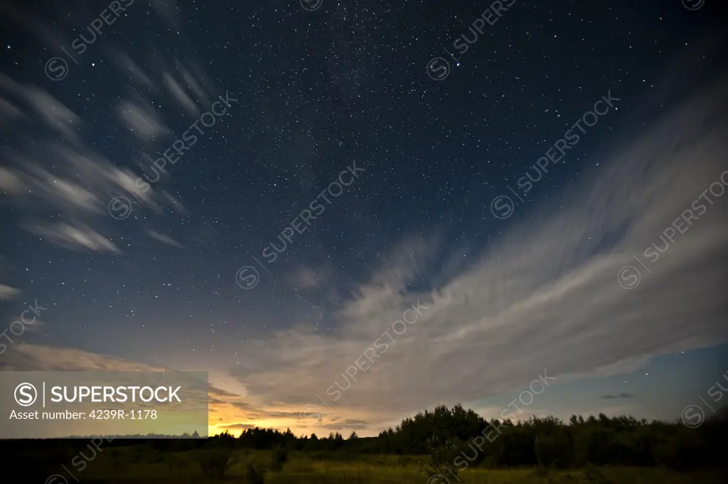 Clouds reflecting the city glow in Alberta, Canada, under a celestial sky