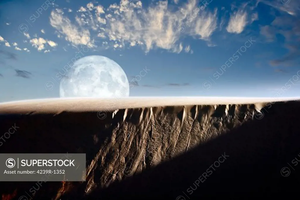 A larger than life depiction of the full moon rising above a sand dune at White Sands National Monument, New Mexico