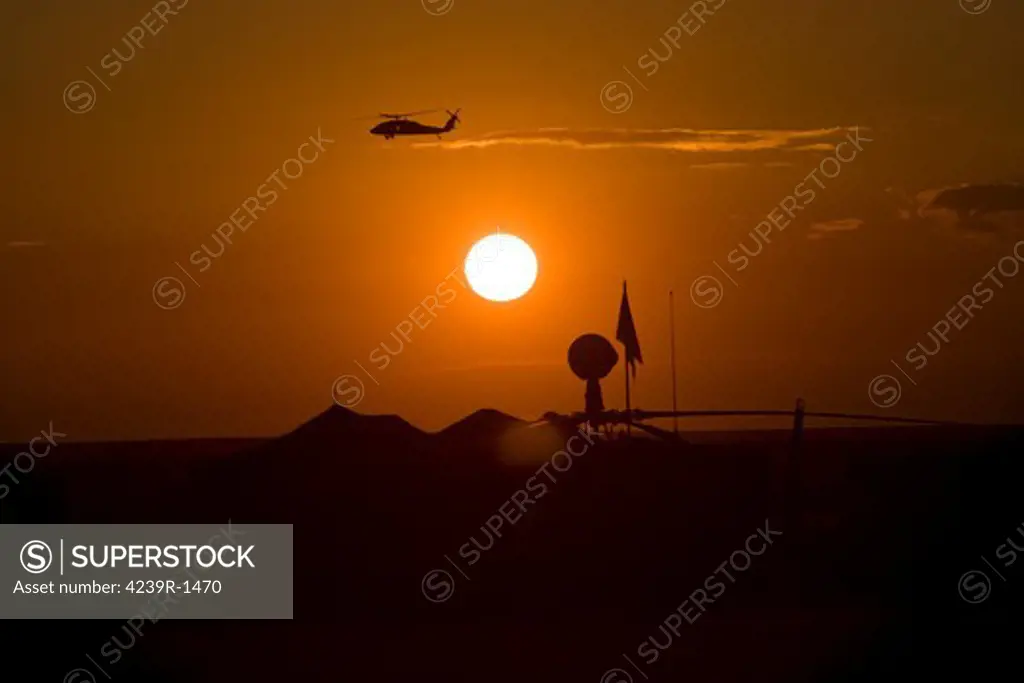 Camp Speicher, Iraq - UH-60 Blackhawk flies over Camp Speicher airfield at sunset
