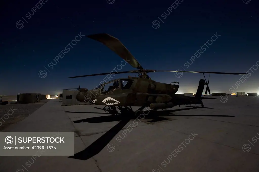 An AH-64D Apache Longbow Block III attack helicopter waits on the flight line at night at Camp Speicher