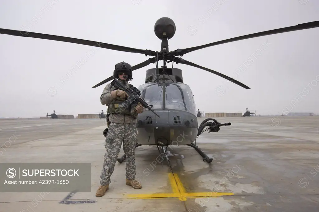 An OH-58D Kiowa Warrior pilot stands beside his aircraft