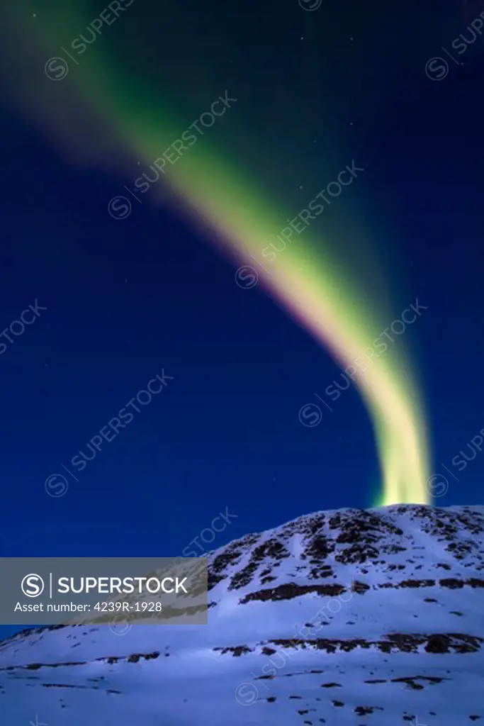 A magnificent display of aurora borealis shooting up from Toviktinden Mountain in Troms County, Norway. Auroras are the result of the emissions of photons in the Earth's upper atmosphere.