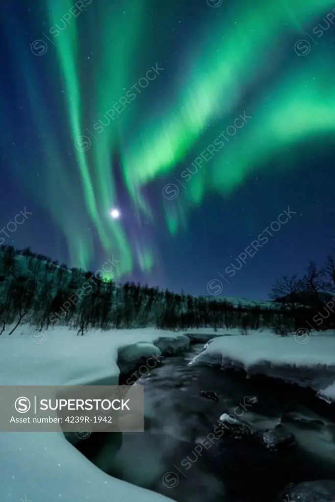 Aurora Borealis over Blafjellelva River in Troms County, Norway. Auroras are the result of the emissions of photons in the Earth's upper atmosphere.