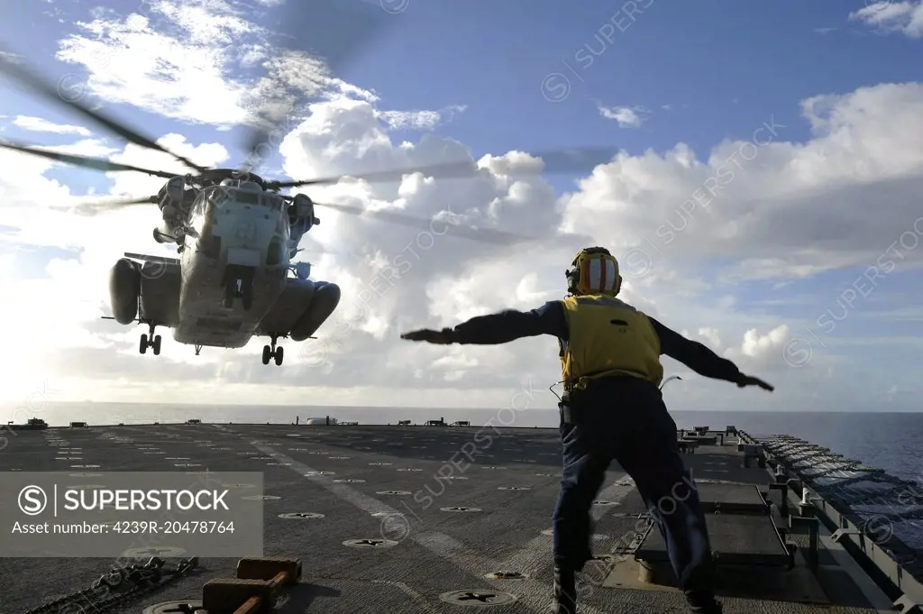 East China Sea, September 11, 2010 - Aviation Boatswain's Mate directs a CH-53E Super Stallion helicopter aboard the amphibious dock landing ship USS Harpers Ferry. Harpers Ferry is on patrol in the western Pacific Ocean and is part of the permanently forward-deployed Essex Amphibious Ready Group.