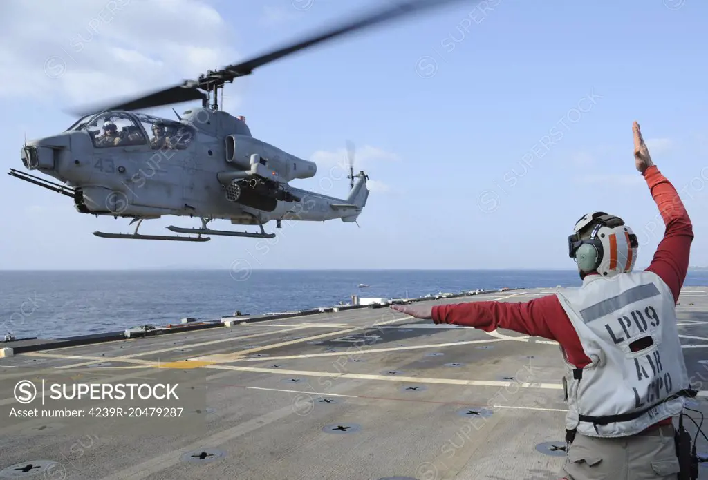 Pacific Ocean, April 4, 2012 - Chief Aviation Boatswains Mate signals to the pilot of an AH-1W Cobra helicopter as it takes off from the amphibious transport dock ship USS Denver (LPD 9). 