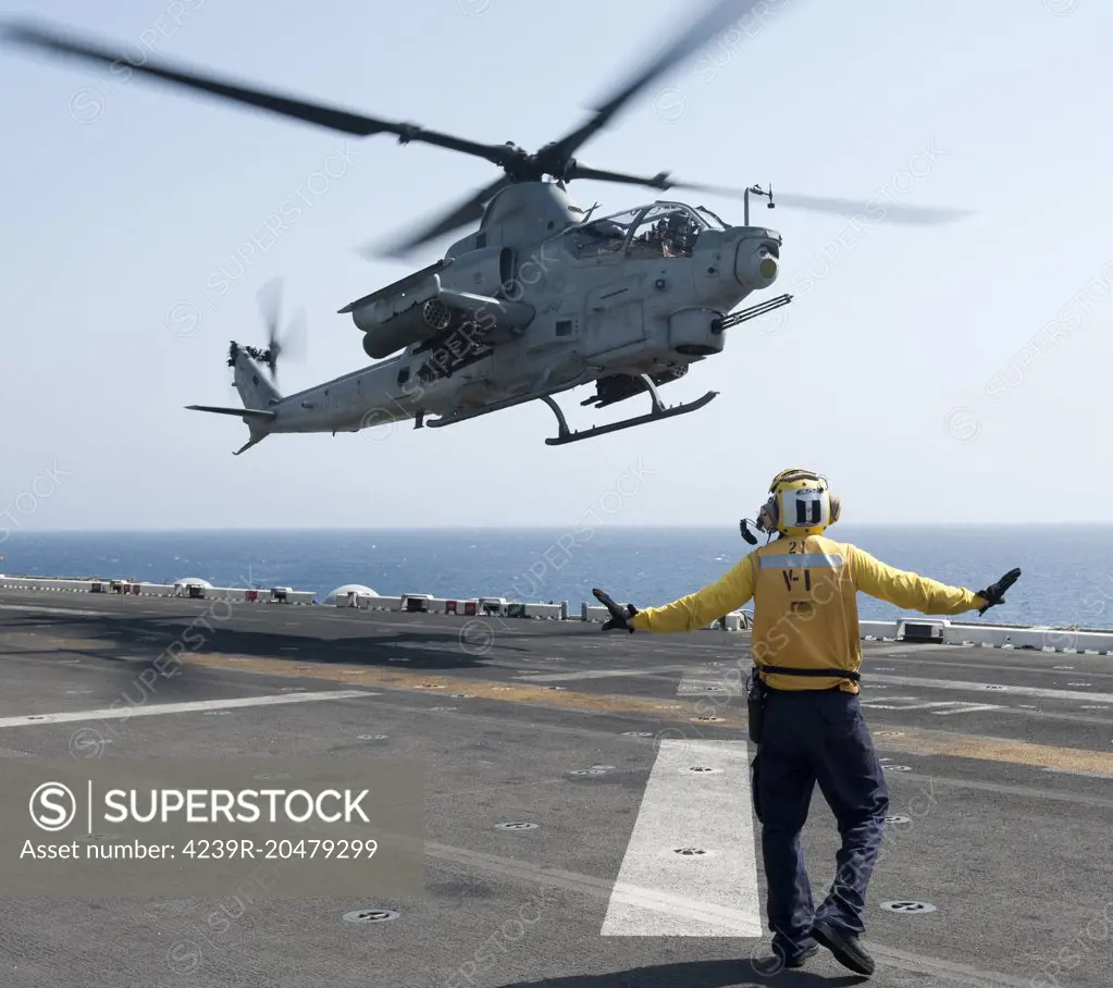 Red Sea, April 16, 2012 - An aircraft handler signals to an AH-1Z Cobra helicopter as it takes off from the amphibious assault ship USS Makin Island (LHD 8). 