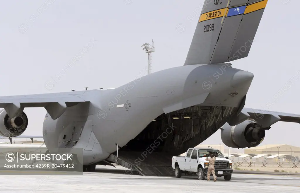 March 27, 2010 - A U.S. Airman marshals a truck into a C-17 Globemaster III aircraft at the flight line of an undisclosed location in Southwest Asia. 