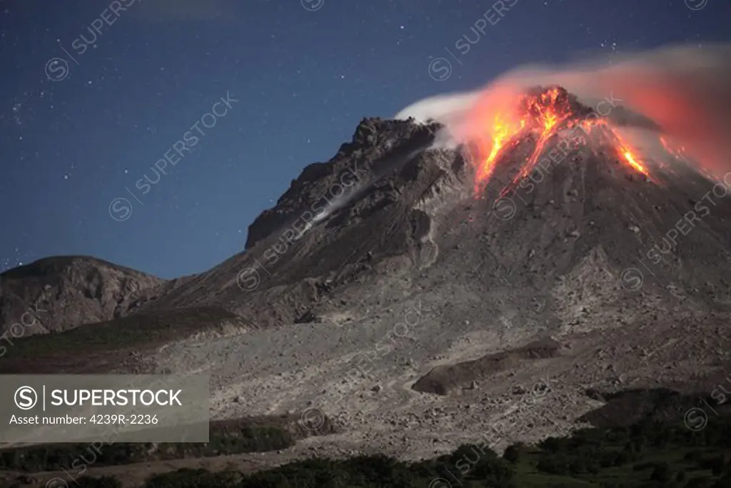 January 28, 2010 - Nighttime view of glowing lava dome in moonlight, during eruption of Soufriere Hills volcano, Montserrat, Caribbean.