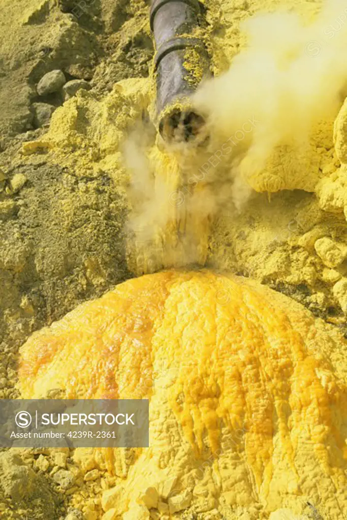 Condensated liquid sulphur running out of a pipe in Kawah Ijen Volcano Sulphur Mine, Java, Indonesia