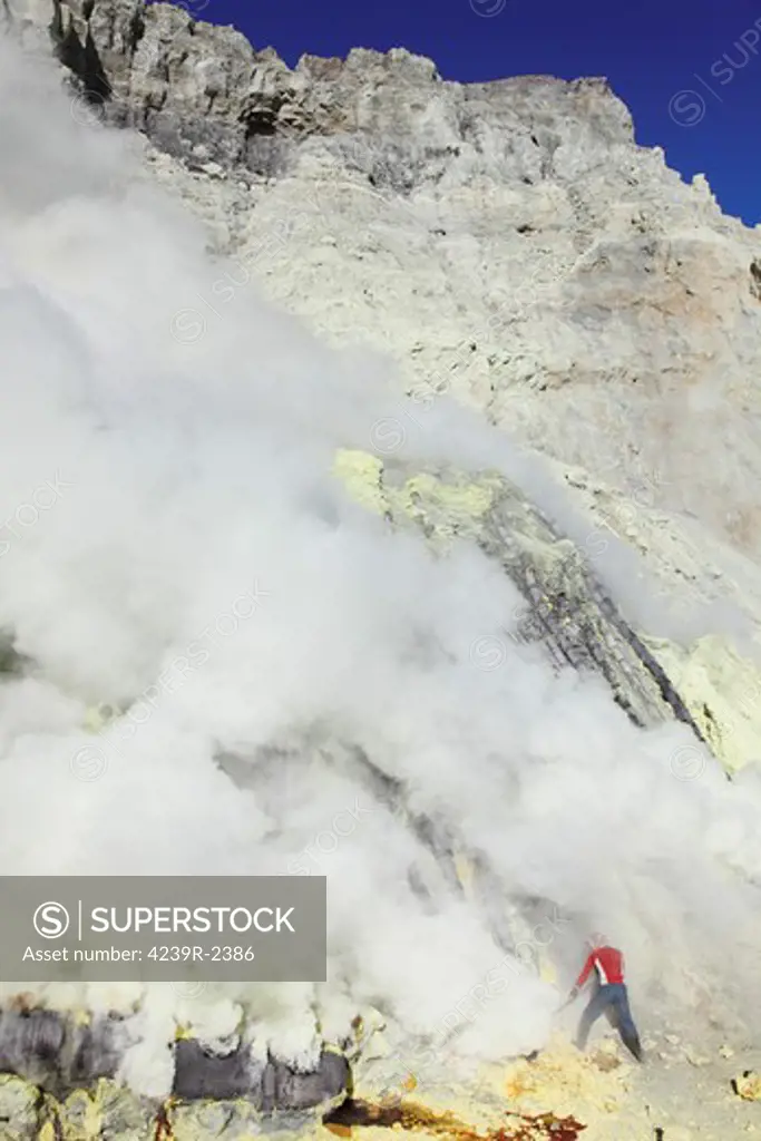 August 13, 2011 - Miner breaking up sulfur deposits at base of condensation pipes, Kawah Ijen volcano, Java, Indonesia.