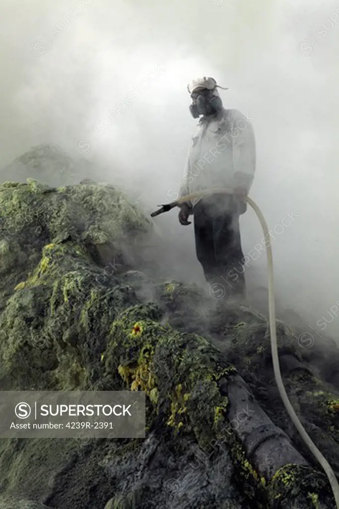 August 13, 2011 - Miner waits for water to cool piping on sulphur mine, Kawah Ijen volcano, Java, Indonesia.