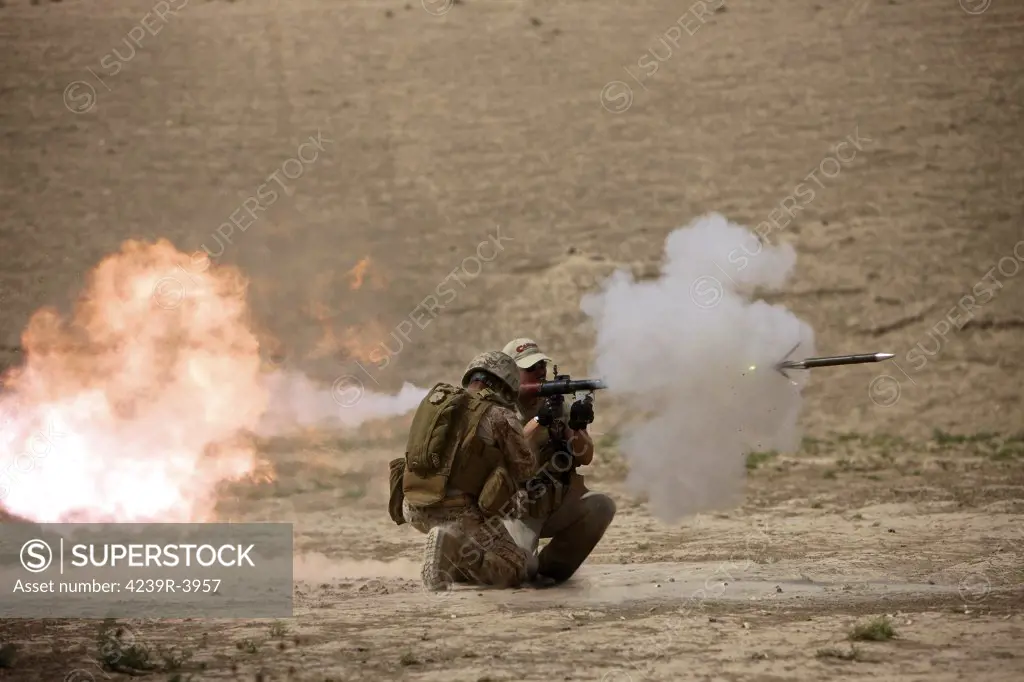 U.S. Marine watches a U.S. Contractor fire a HE fragmentation round from the RPG-7 rocket-propelled grenade launcher in a wadi near Kunduz, Afghanistan.