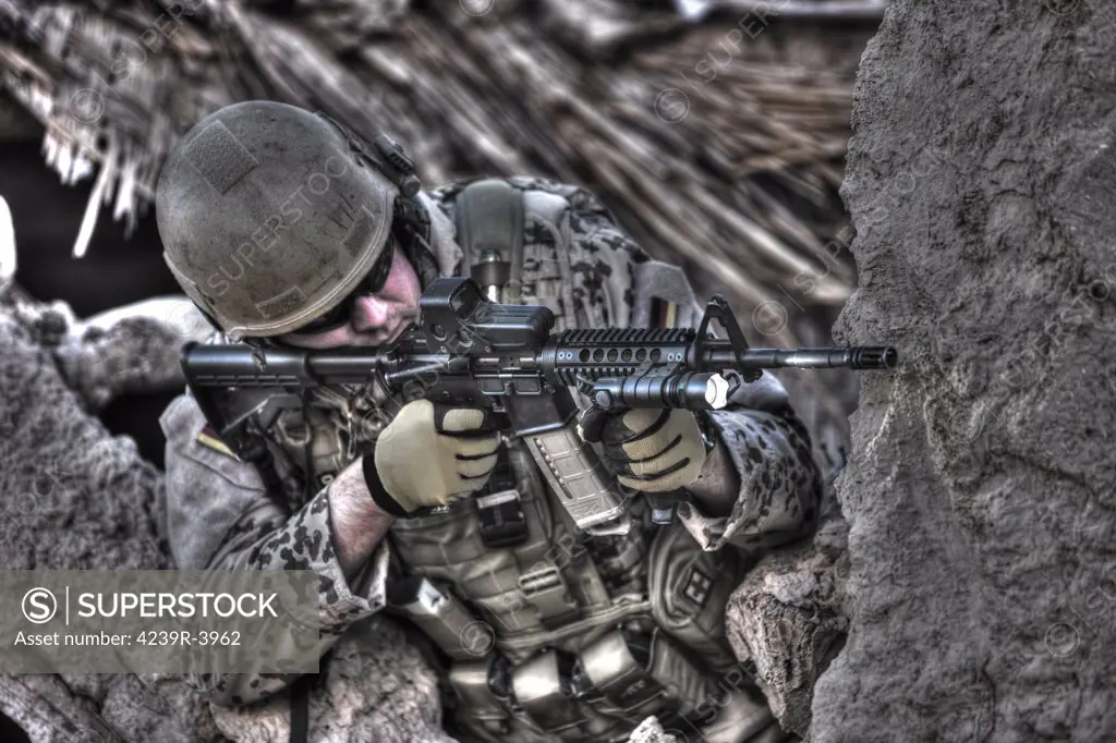 High Dynamic Range image of a German Army soldier armed with a M4 carbine assault rifle in the ruins of a Afghan building.