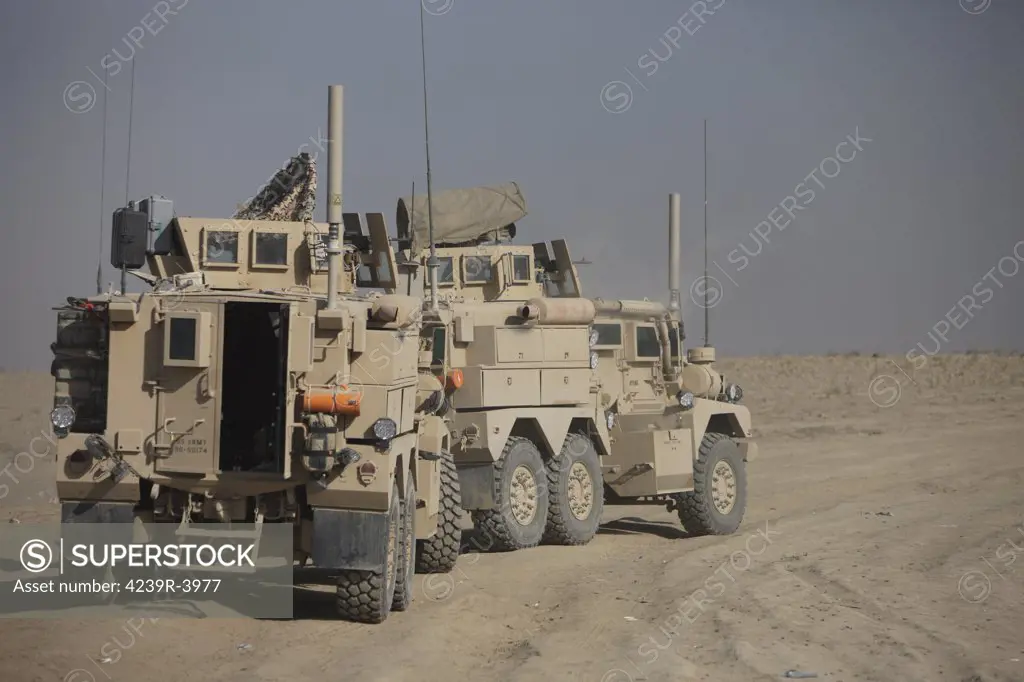 U.S. Army Cougar MRAP vehicles parked overlooking the top of a wadi during a weapons familiarization shoot in Kunduz, Afghanistan.