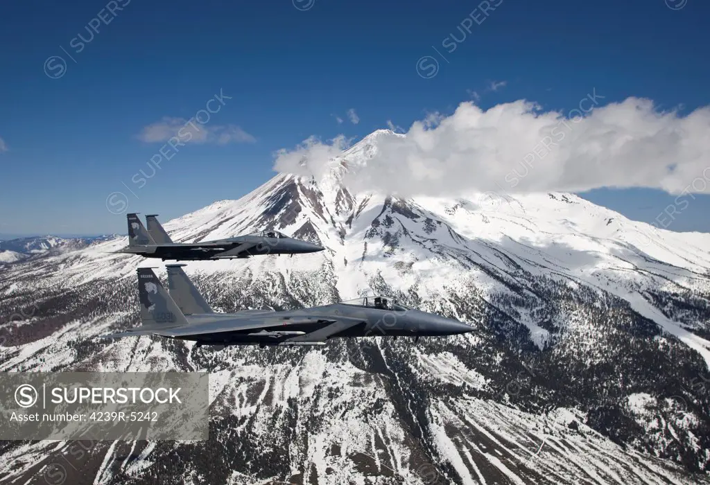 Two F-15 Eagles from the 173rd Fighter Wing fly past snow capped peaks in Central Oregon.