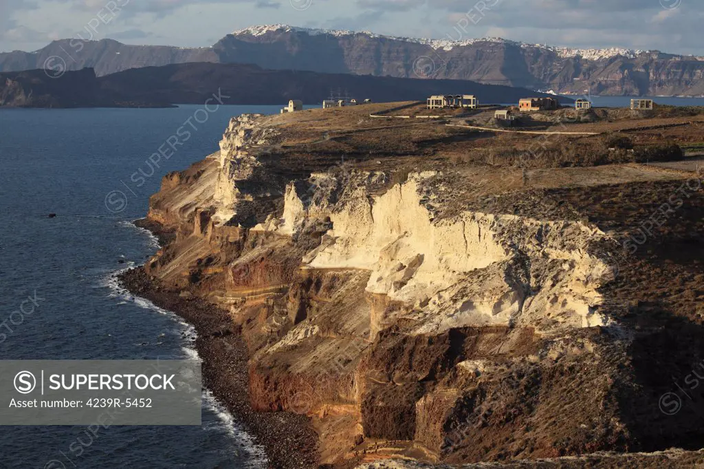 Cliffs of Cape Apronisi exposing cycle 1 eruption products covered with the lighter tuff deposits from the Minoan Eruption of Santorini Volcano. Kameni Islands and main Caldera wall are in background.