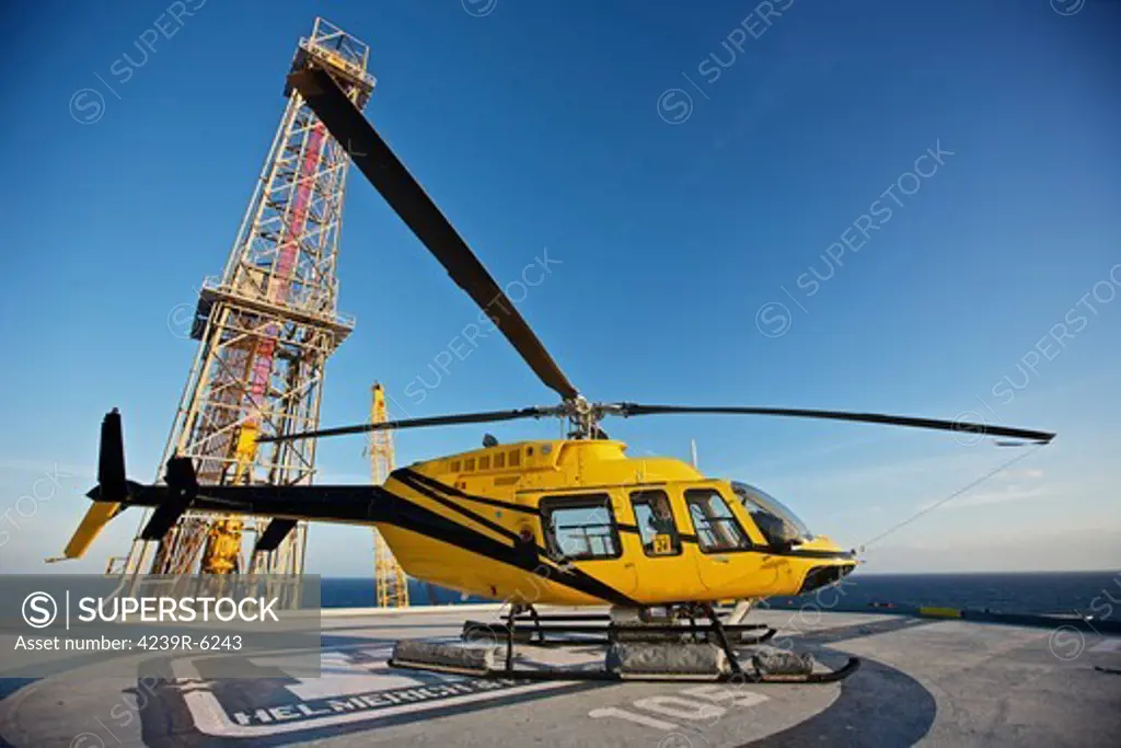 A Bell 407 utility helicopter on the helipad of an oil rig.