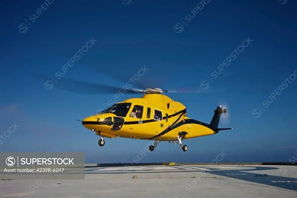 A Sikorsky S-76 utility helicopter taking off from an oil rig.