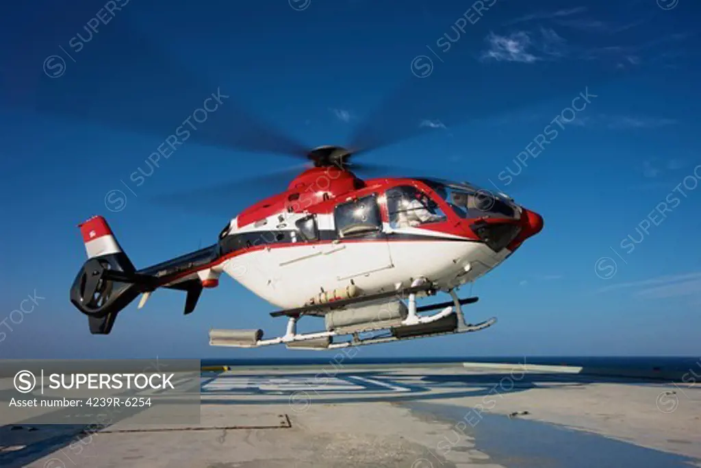 Eurocopter EC135 utility helicopter on the helipad of an oil rig.