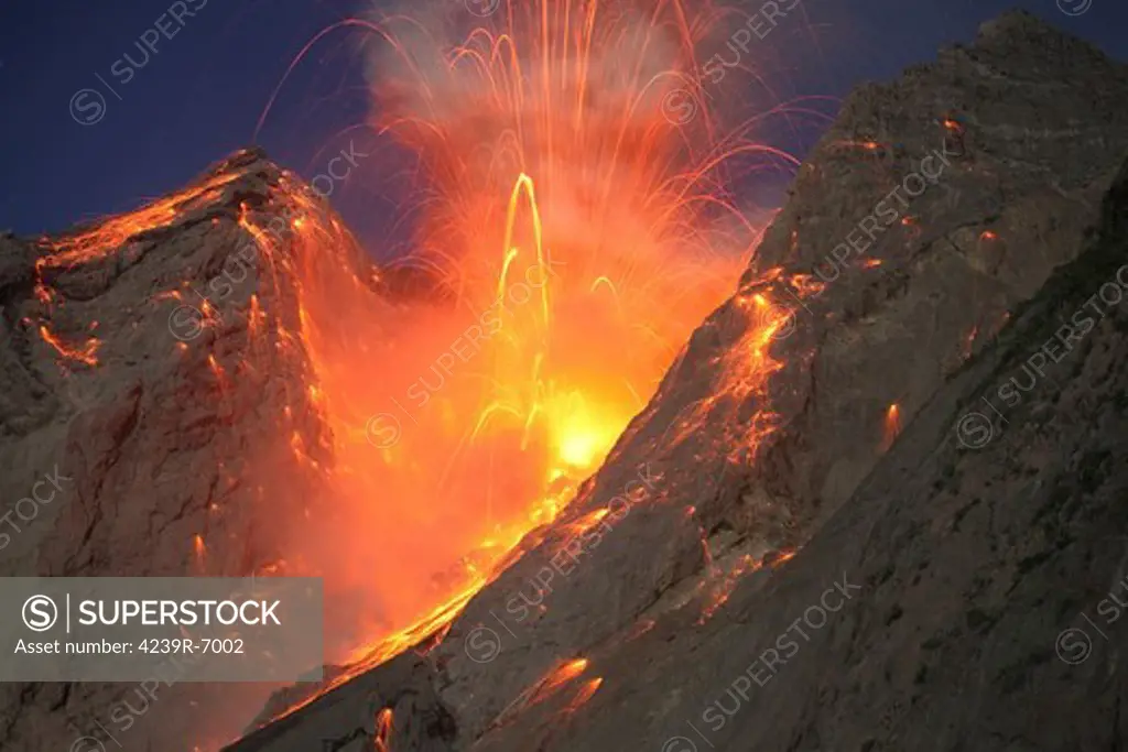November 28, 2012 - Explosive strombolian type eruption of Batu Tara volcano, Komba Island, Indonesia. Trajectories of red glowing lava bombs are visible against blue night sky.