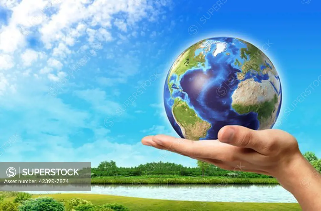 Human hand holding Earth globe with a beautiful green landscape and river background.