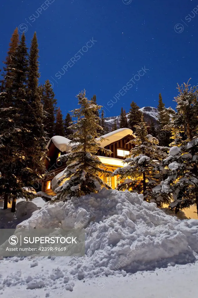 February 4, 2012 - A moonlit nightscape with a gibbous moon providing illumination of a scene with Orion over Mount Fairview and a home at Lake Louise, Alberta, Canada.