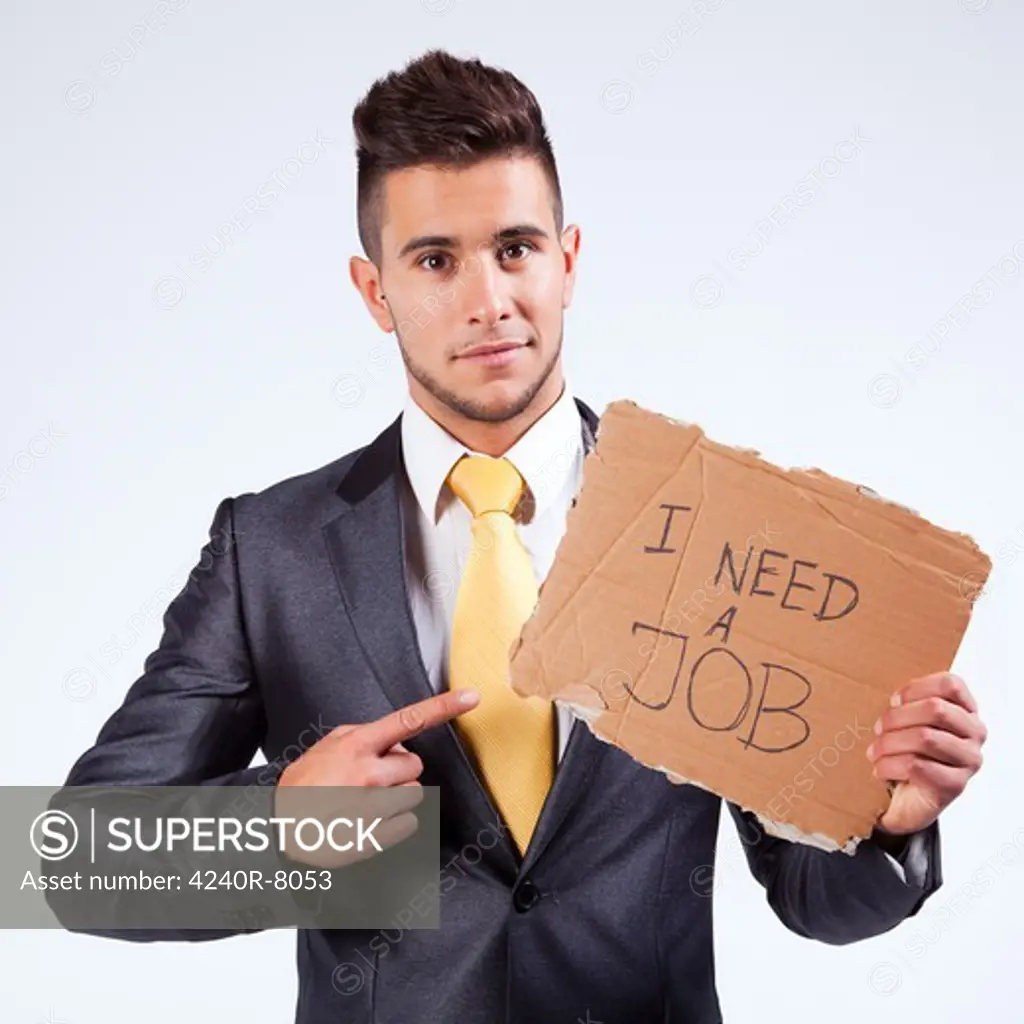 Young Businessman Holding A Piece Of Cardboard Saying He Needs A Job