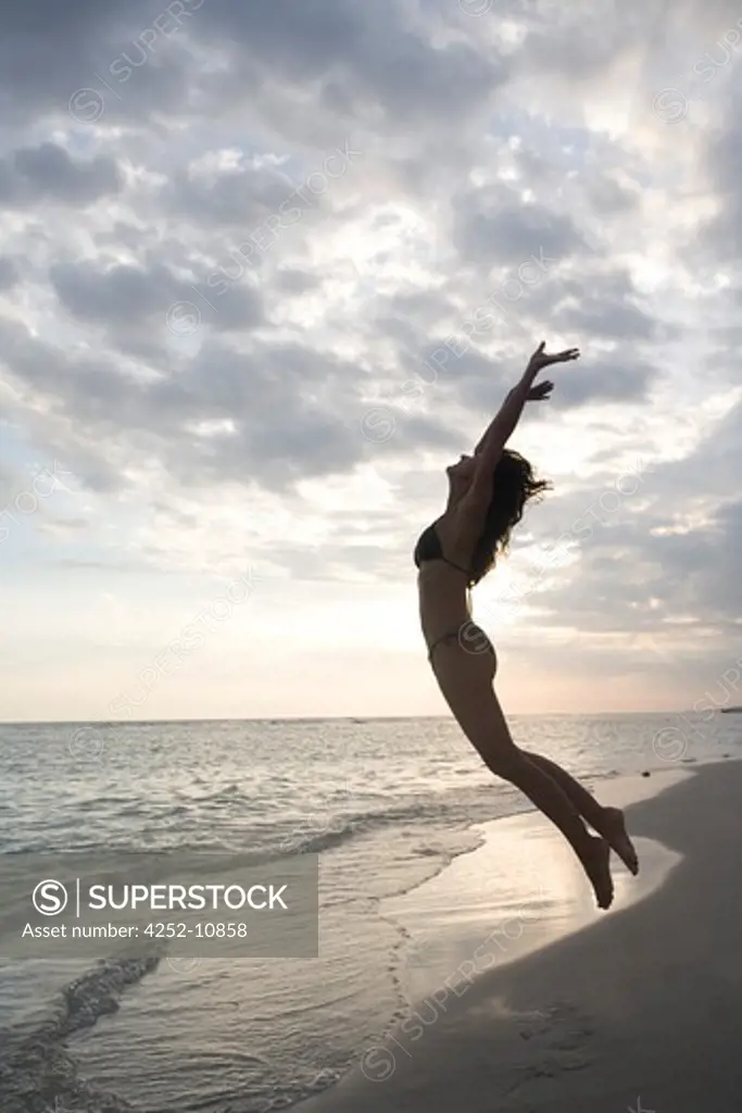 Woman jump beach.