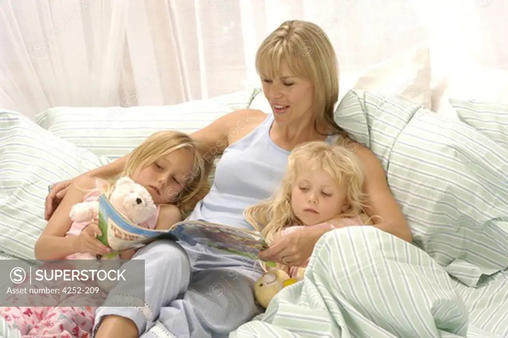 Mother reading a book to her daughters