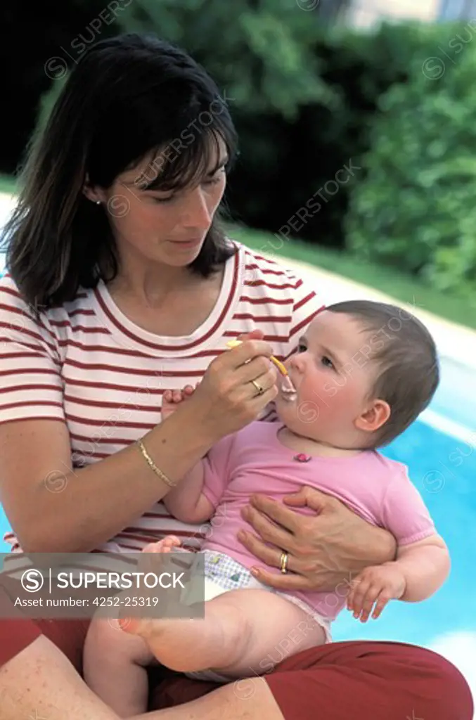 family outside child woman baby food swimming pool summer eating spoon afterschool snack girl mother