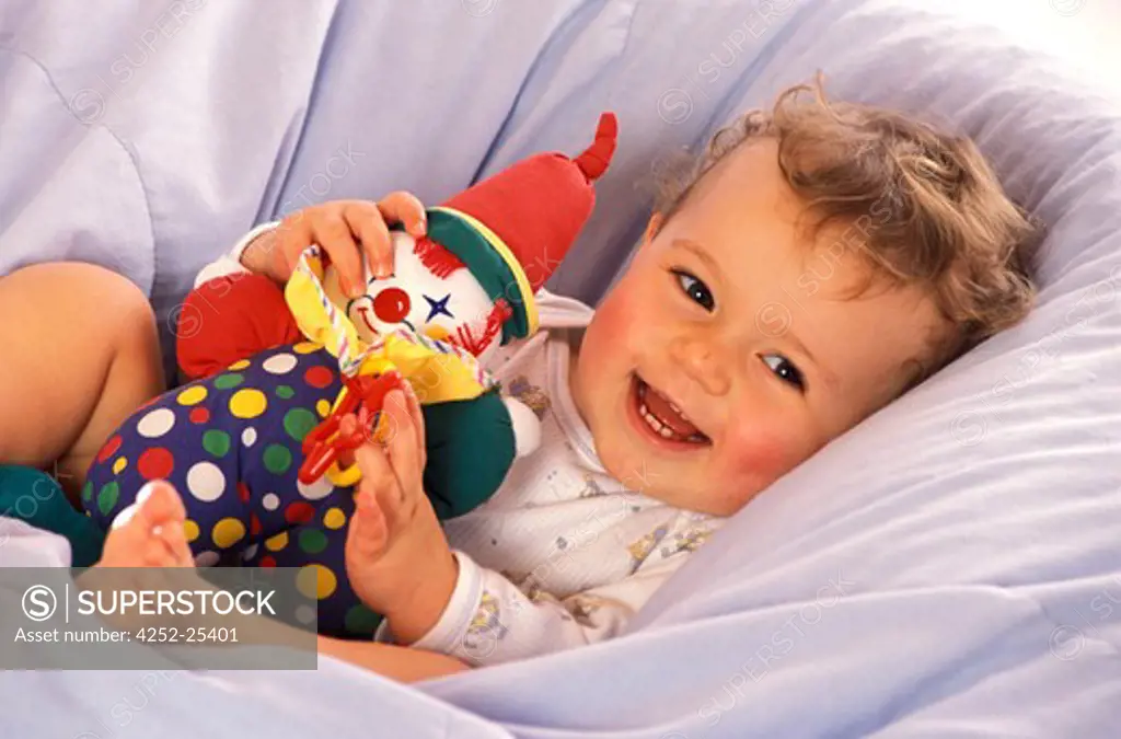 children inside boy baby joy lying duvet soft toy clown smiling