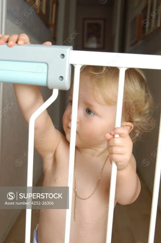 Baby girl standing behind safety barrier