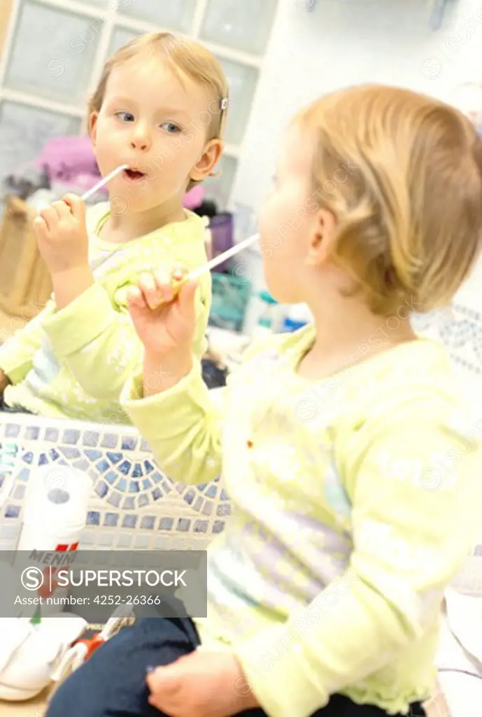 Little girl looking in miror and brushing her teeth