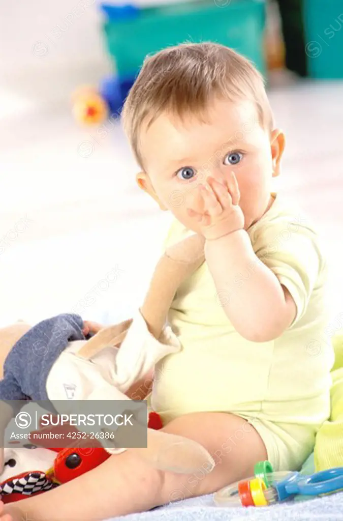 Baby sucking his thumb and holding fluffy toy
