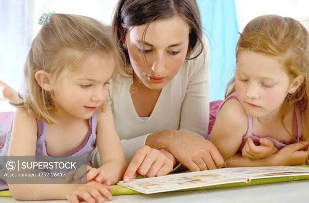 Woman and two little girls looking at book