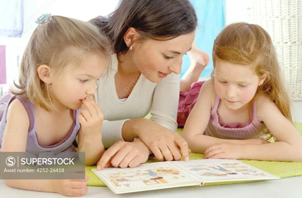 Woman and two little girls looking at book