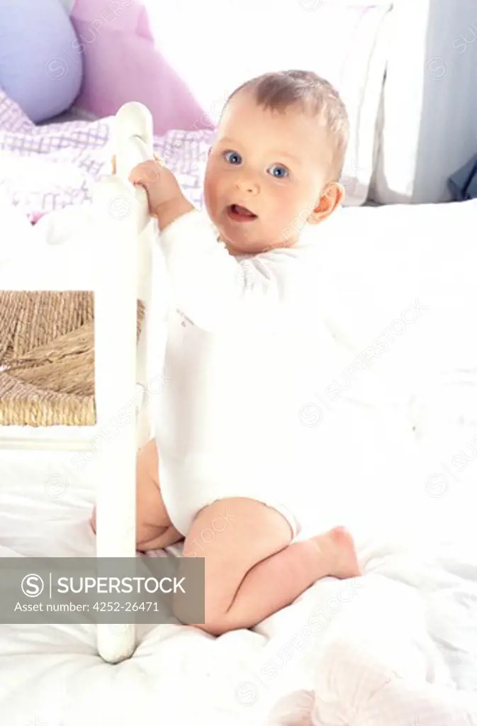 Baby kneeling, holding on to a little chair