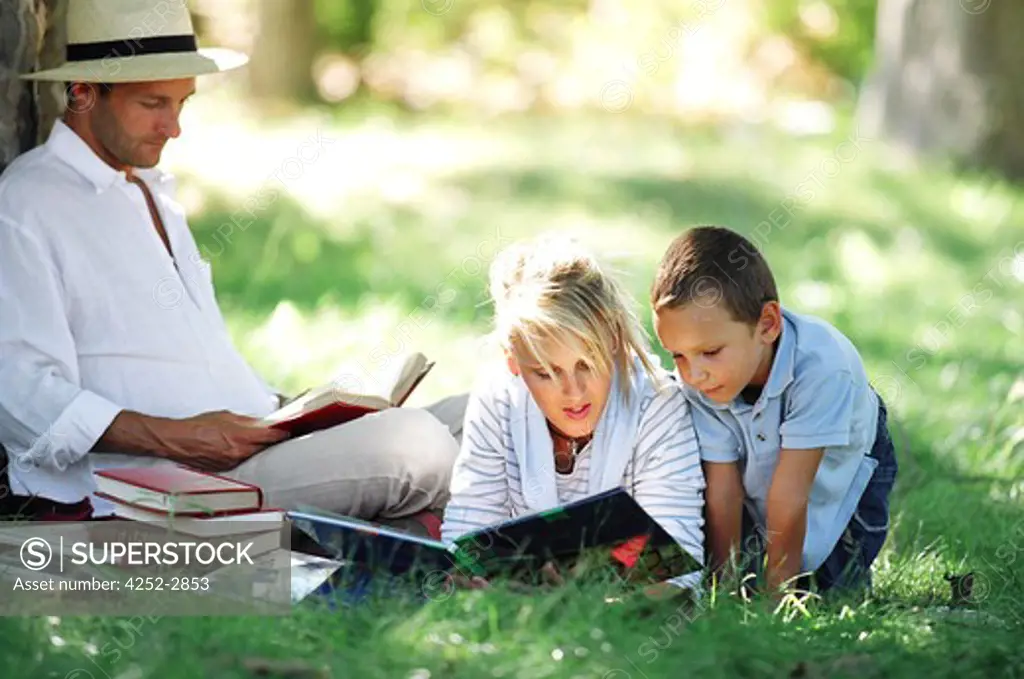 Family reading in the shade of tree
