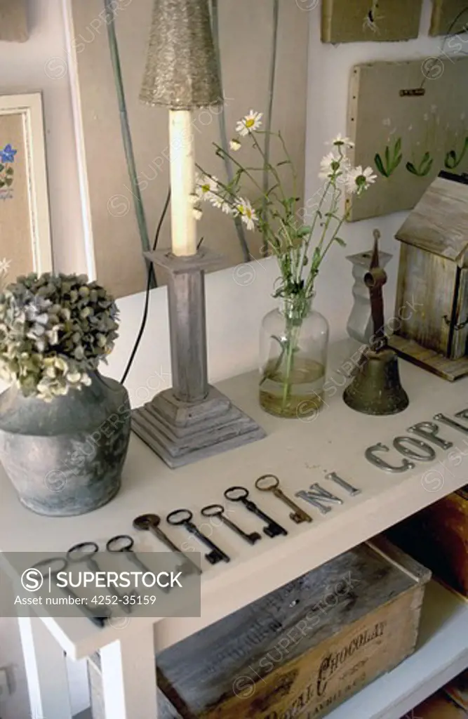 White console table with a key collection, vases and lamp on it