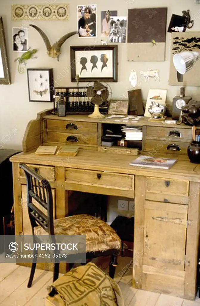 Home office with a wooden old style desk and lots of frames on the wall upon it
