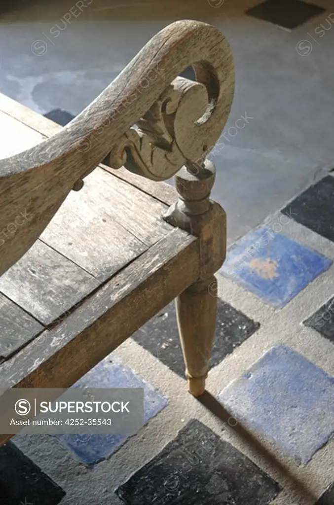 Detail of a wooden antique bench located into the library room with a blue and grey tiled floor