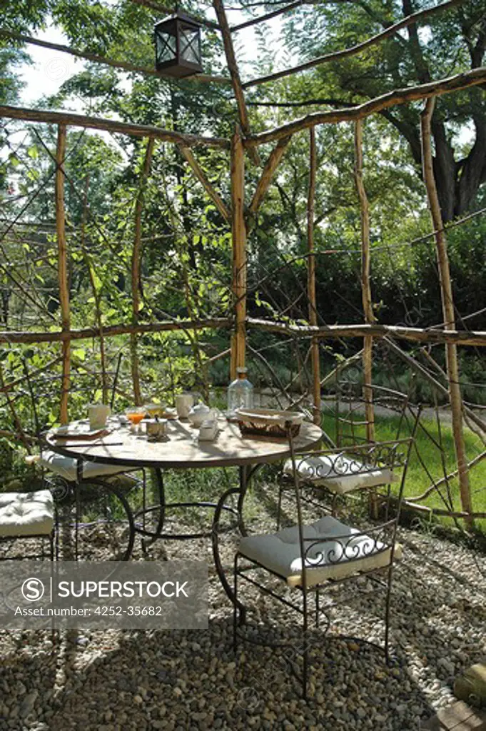 Wooden pergola into a garden with table and chairs in the middle