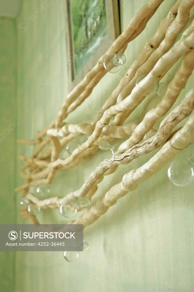 Wooden branches suspension on a green wall with glass bubbles hanging on it