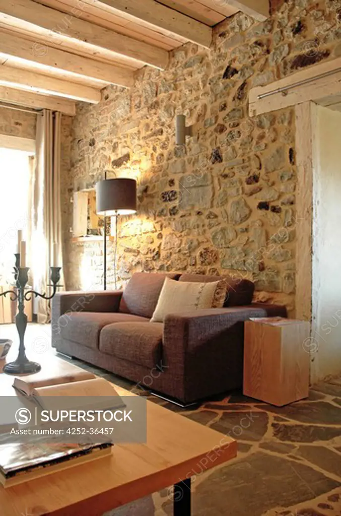 Brown sofa into a living room with stone walls and floors into a country house
