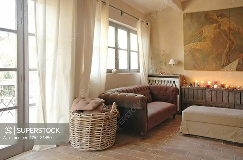 Brown velvet sofa into a beige living room with tiled floor and big wicker basket filled with cushions