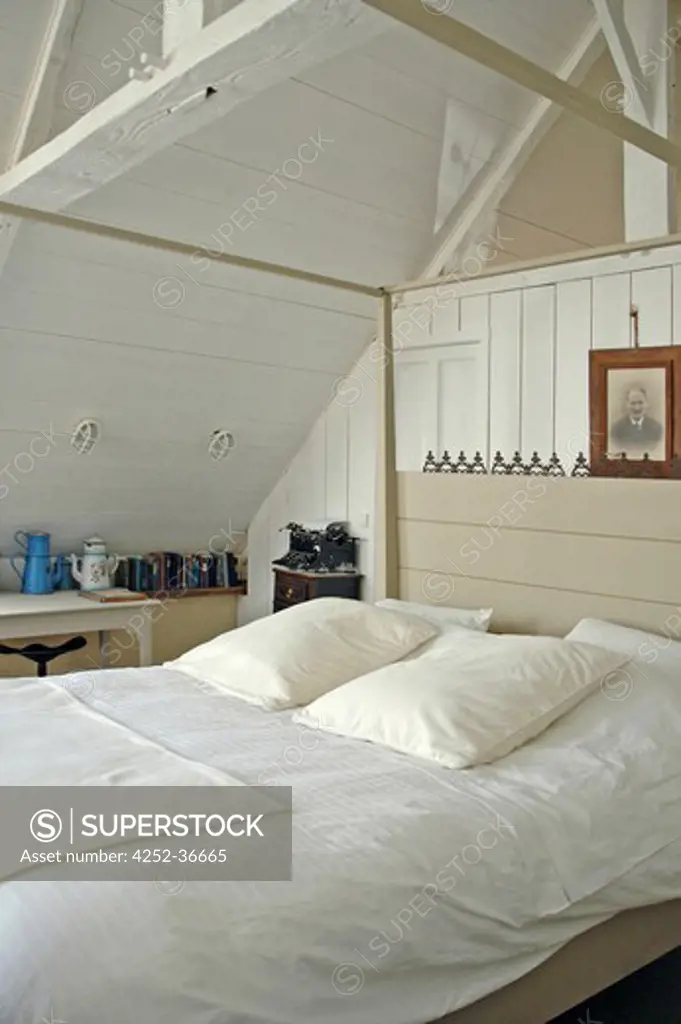 White attic bedroom with a four-poster bed