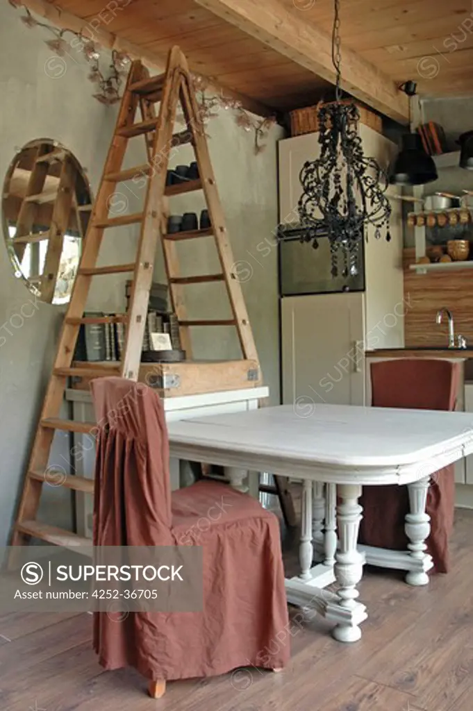 Table and chairs into an open kitchen with a ladder used as a shelf