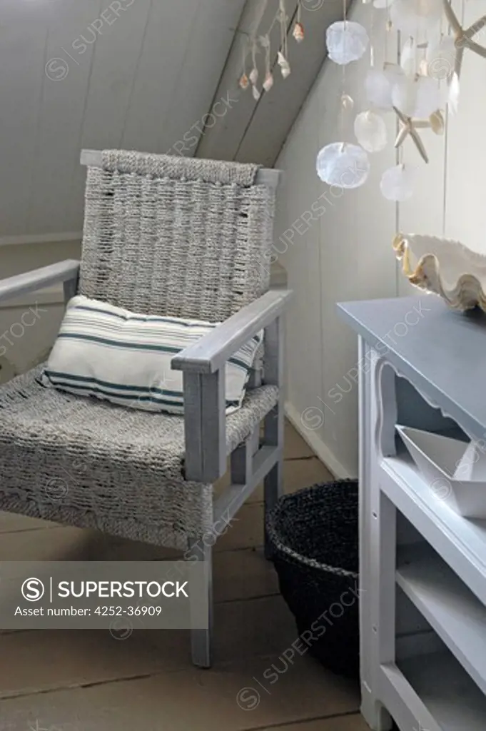 Wicker chair and shell suspension into an attic beige bedroom