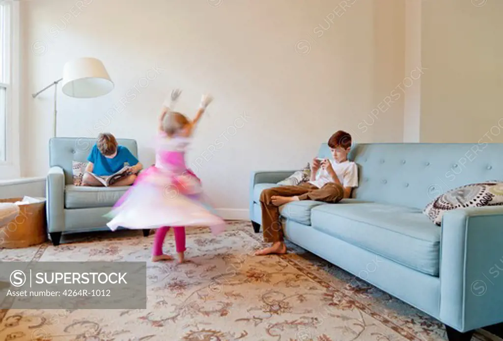 Girl dancing in princess costume, boys reading and playing on phone in background